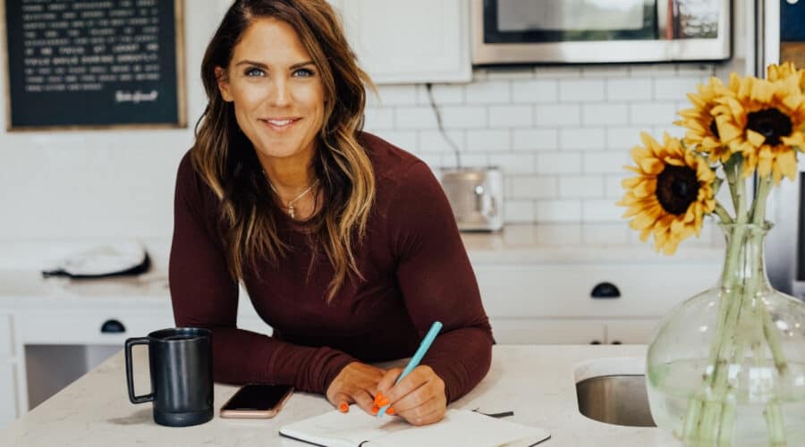 woman holding pen and writing down New Year's resolutions in her notebook